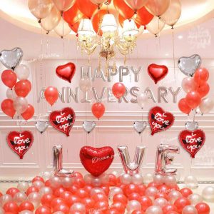 Happy Anniversary decoration set featuring 'Happy Anniversary' foil balloons, red LOVE alphabet balloons, heart-shaped foil balloons, romantic red fairy lights, and latex balloons for a special celebration.