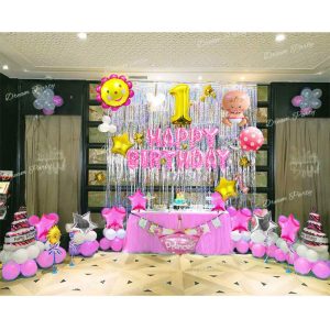 A festive birthday setup foil Balloon featuring a pink "Happy Birthday" foil banner, silver foil curtains, a gold digit balloon, flower and baby girl balloons, pink cake balloons, a pink crown balloon, star balloons in pink, gold, and silver, and pink and white latex balloons for a cheerful and elegant celebration.