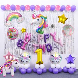 Unicorn themed birthday party decoration set featuring unicorn face, standing unicorn, rainbow foil balloons, printed unicorn balloons, star-shaped foil balloons, and silver backdrop curtains."
